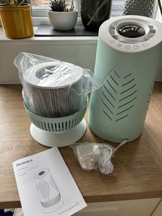 a green blender sitting on top of a wooden counter next to a potted plant