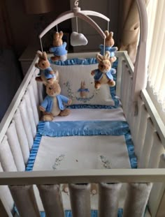 baby crib with teddy bears in blue and white bedding, hanging from the ceiling