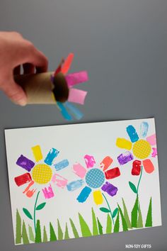 someone is painting flowers on a card with crayons and paper straws to make it look like they are holding something in their hands