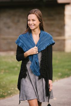 a woman is walking down the street wearing a blue shawl and black cardigan