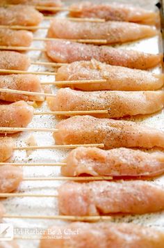 chicken skewers are lined up on a baking sheet