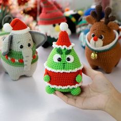 hand holding small christmas ornaments in front of many other stuffed animals and toys on a table