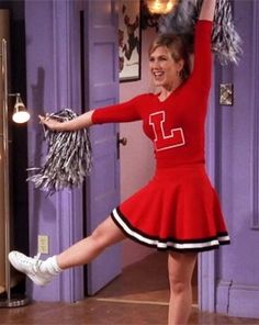 a woman in a red cheerleader outfit is dancing on the floor with her hands up