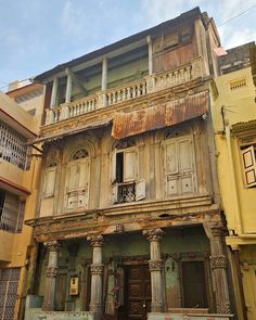 an old building with wooden doors and balconies on the outside, next to other buildings