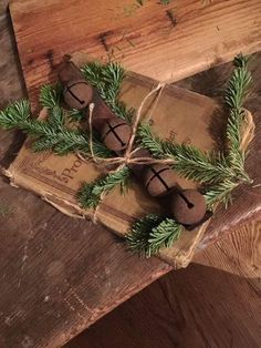 three wooden bells tied with twine on top of a piece of wood next to pine branches