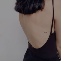 the back of a woman's neck with small tattoos on her left shoulder and right arm