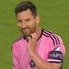 a man with a goatee smiles at the camera while standing on a soccer field