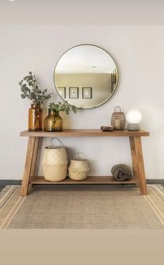 a wooden table topped with a mirror and vases next to a shelf filled with baskets