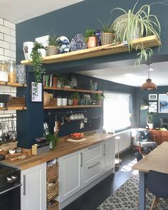 a kitchen with blue walls and shelves filled with pots, pans and other items