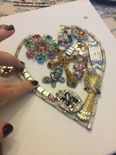 a woman's hand is holding an assortment of brooches on a piece of paper