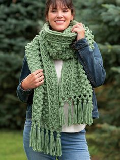 a woman wearing a green knitted scarf with fringes on her neck and shoulders