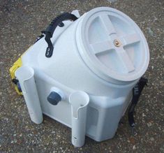 a white cooler sitting on top of a cement ground next to a yellow and black handle