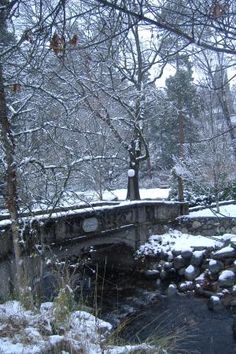 a small stone bridge over a stream in the snow