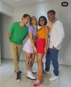 four people posing for the camera in front of a white wall and tile flooring