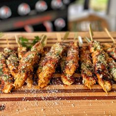 several skewers of food sitting on top of a wooden cutting board