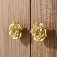 two gold flower knobs sitting on top of a wooden door