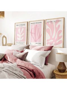 a bed with pink sheets and pillows next to two pictures on the wall above it