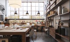 a room filled with lots of books and furniture next to a tall window covered in windows