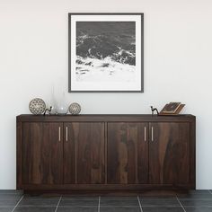 a wooden cabinet with two vases on top of it next to a framed black and white photo