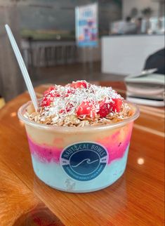 an ice cream sundae with strawberries and coconut flakes in a plastic cup