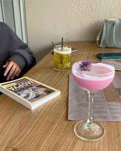 a person sitting at a table with a book and drink