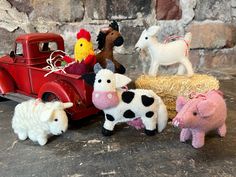 several farm animals sitting on hay next to an old red truck and toy horse, lamb, chicken, pig