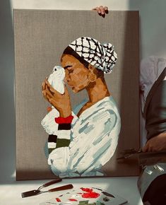 a woman sitting in front of a painting holding a white bird and looking at it