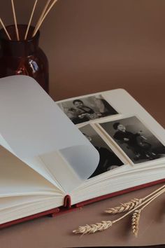 an open book sitting on top of a table next to a vase filled with flowers