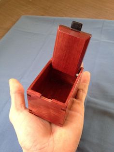 a hand holding an open wooden box on top of a blue sheet