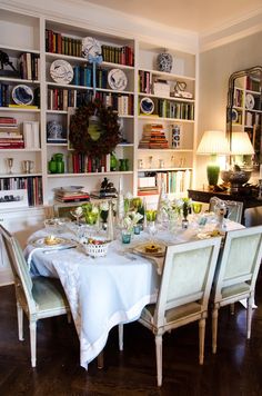 the dining room table is set with plates and glasses on it, along with bookshelves full of books