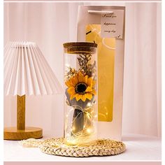 a glass vase with sunflowers in it sitting next to a lamp