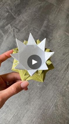 someone is holding an origami flower in their hand with the video below it