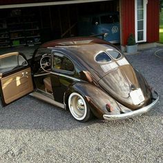 an old car is parked in front of a garage with its doors open and the door ajar