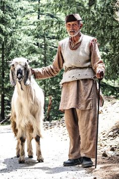 an old man is walking with his goat