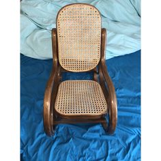 a wooden rocking chair with caned back and seat, on a blue sheeted bed