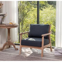 a chair sitting in front of a window next to a table with books on it