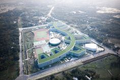 an aerial view of a large building surrounded by lots of green grass and buildings in the background