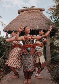 three women dressed in native garb and holding their hands up to the sky while standing next to each other