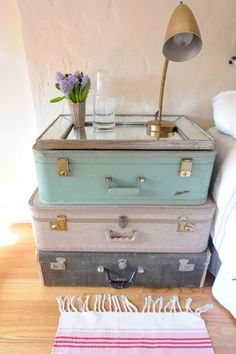 four suitcases stacked on top of each other in front of a lamp and rug