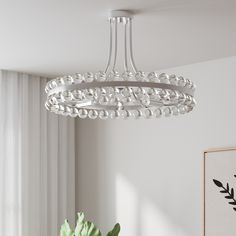 a white chandelier hanging from the ceiling in a room with a potted plant