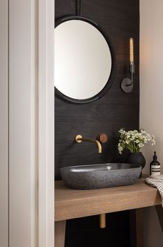 a bathroom sink sitting under a mirror next to a wall mounted faucet with a round mirror above it