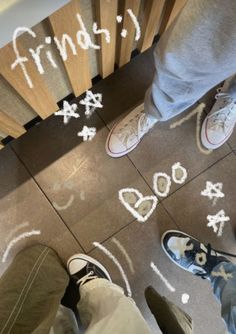 two people standing on the floor with their feet in front of them and writing friends