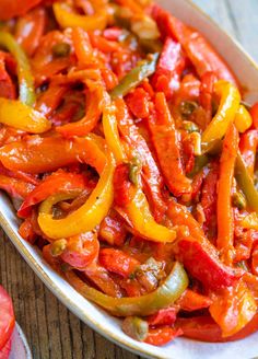 a white dish filled with red and yellow peppers