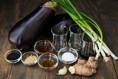 an eggplant, garlic, and other ingredients are arranged on a wooden table