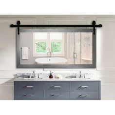 a bathroom vanity with two sinks and a large mirror above it, in front of a window