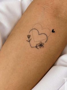 a heart shaped tattoo with flowers on the left side of the arm, and a dotted dot in the middle