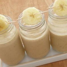 three jars filled with banana smoothies on top of a table