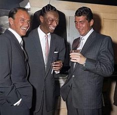 three men in suits standing next to each other holding glasses and smiling at the camera