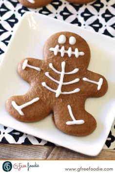 two cookies decorated with white icing on a plate next to another cookie in the shape of a skeleton