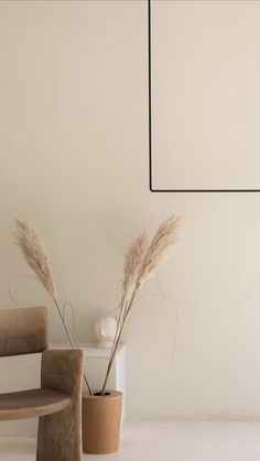 two vases with flowers in them next to a wooden bench and wall hanging on the wall